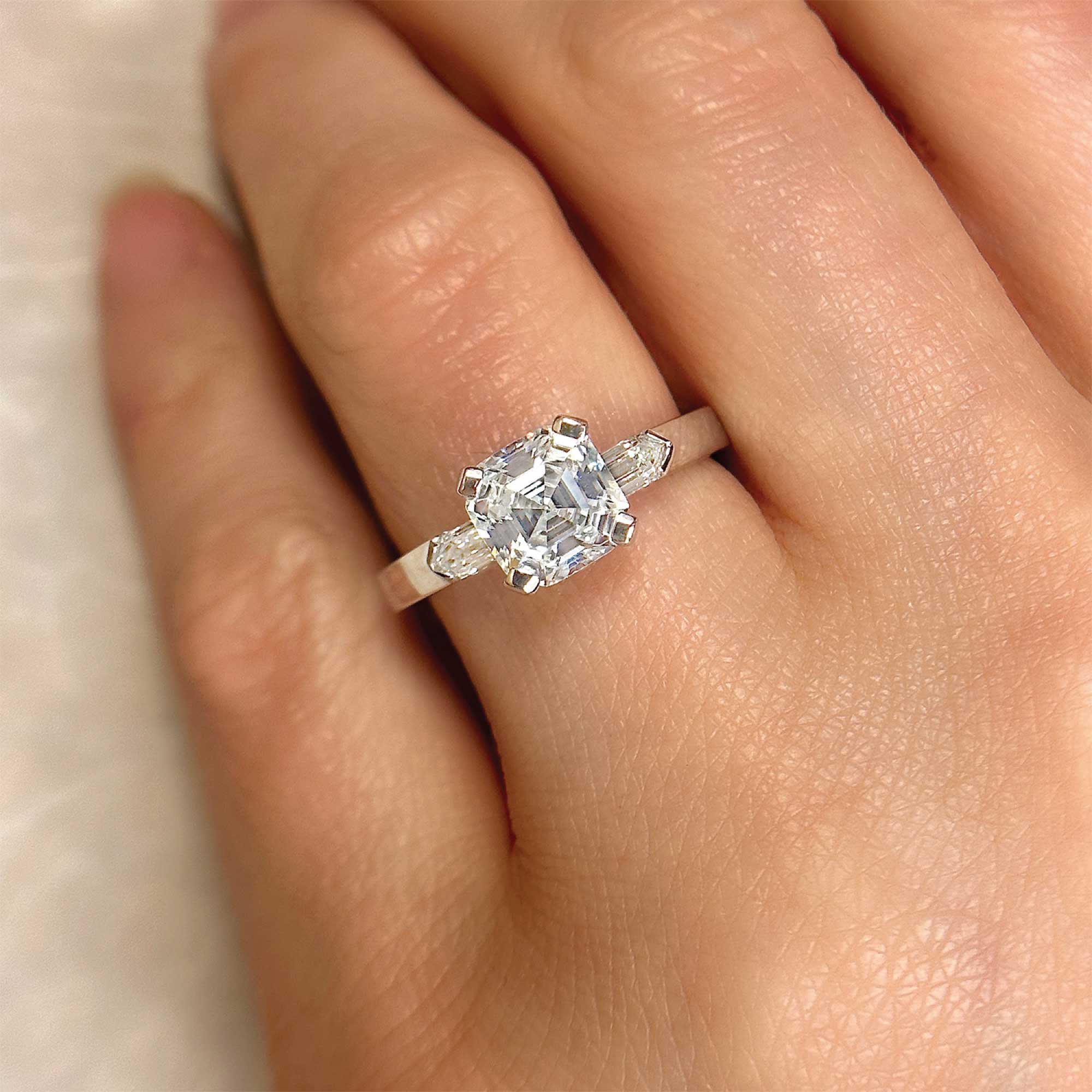 asscher cut diamond engagement ring with bullet cut baguette accents on finger