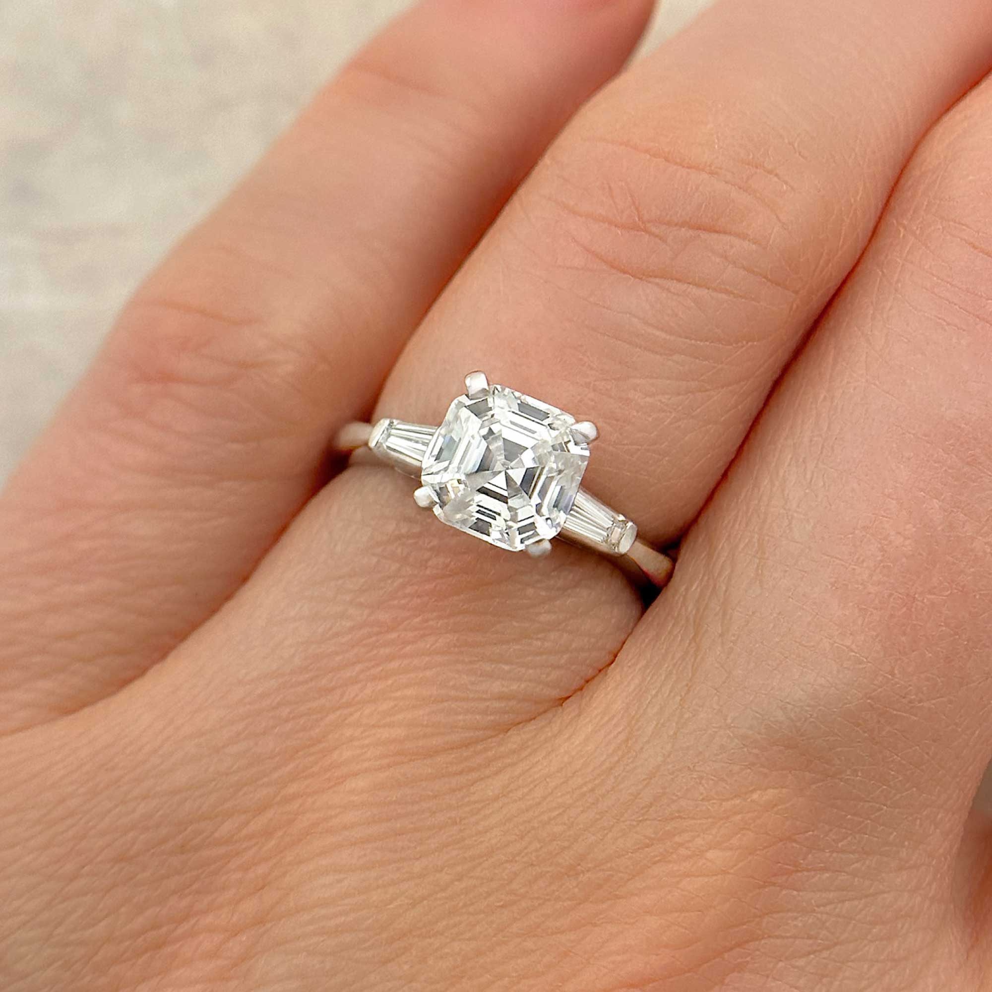assher cut tapered baguette diamond engagement ring on finger alt view