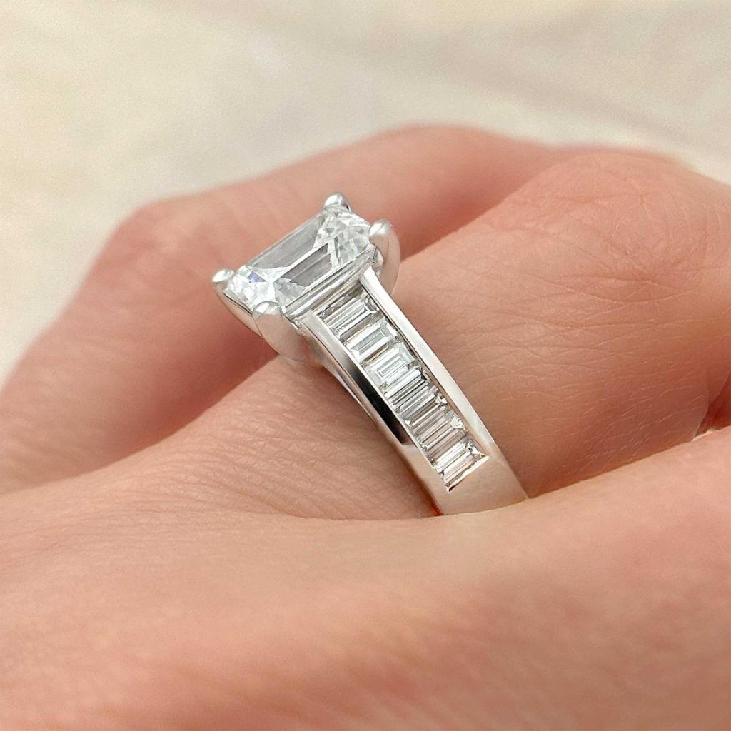 emerald cut diamond engagement ring with channel set baguettes on finger alt view