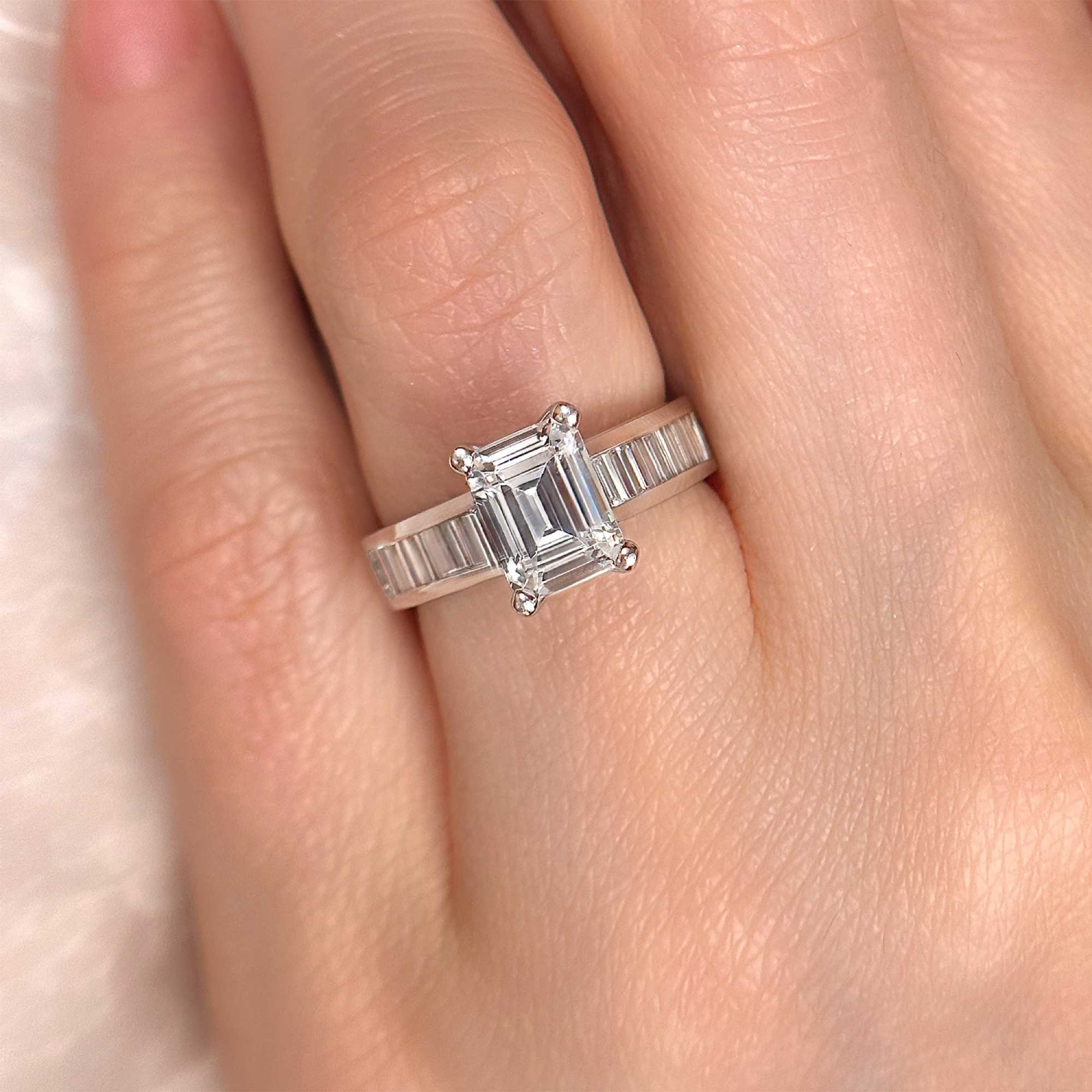 emerald cut diamond engagement ring with channel set baguettes on finger