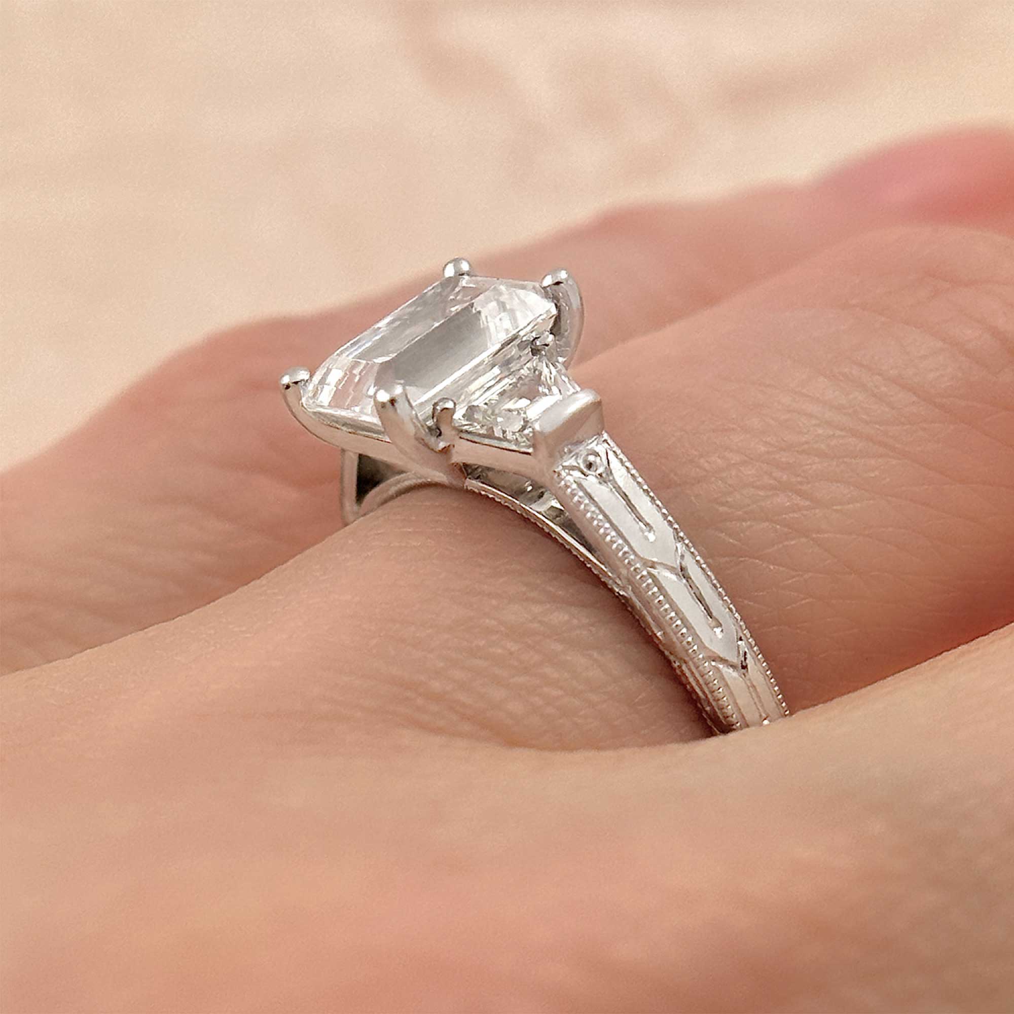 emerald cut diamond engagement ring with trapezoid diamond accents on finger
