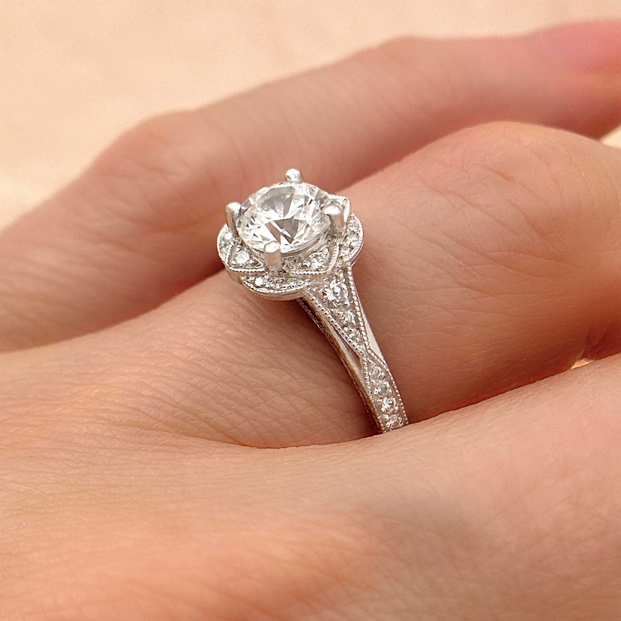 hand engraved round diamond engagement ring with halo on finger
