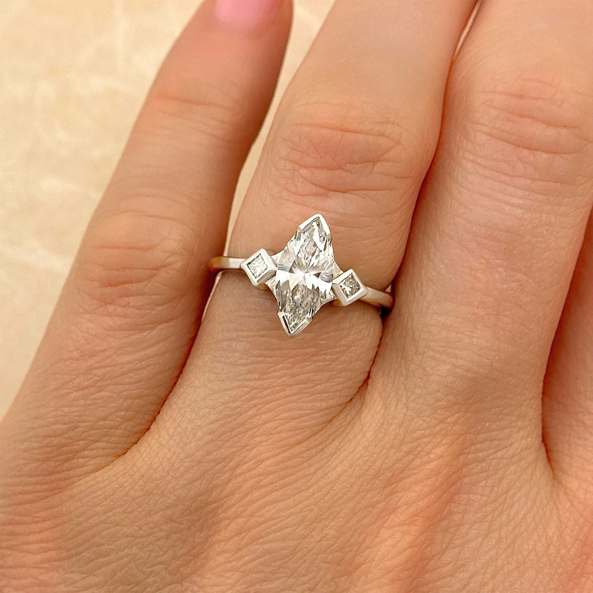 marquise diamond engagement ring with princess cut diamond accents on finger alt view