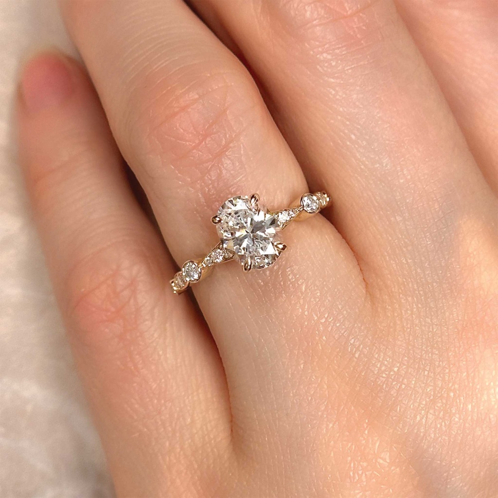 oval diamond engagement ring with articulated pave set diamond band on finger