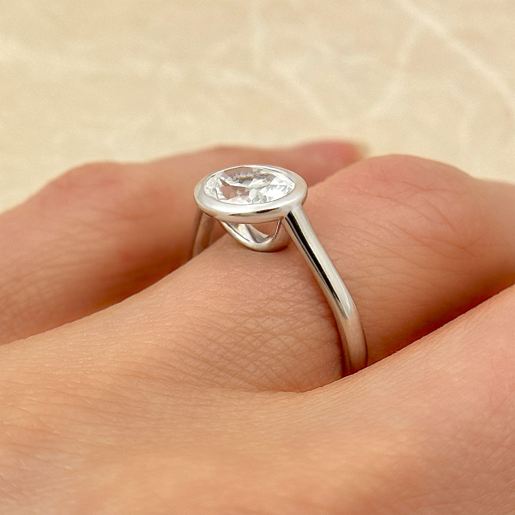 oval diamond solitaire engagement ring in an east west bezel setting on finger
