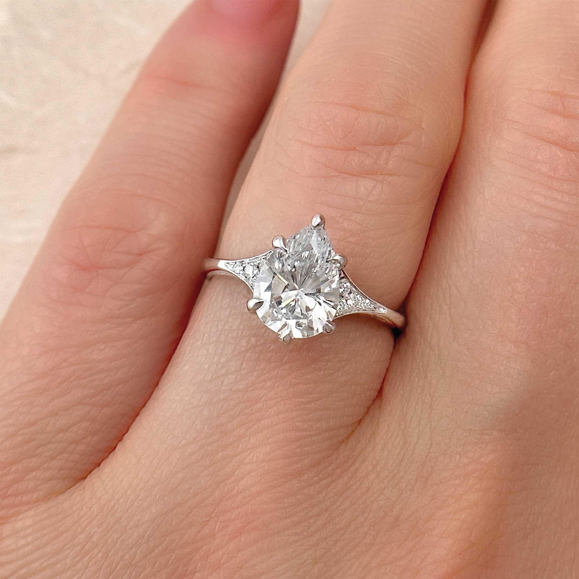 pear-shape-classic-diamond-engagement-ring-with-pave-accents-in-a-streamlined-band-christopher-duquet-fine-jewelry-on-finger-alt-view