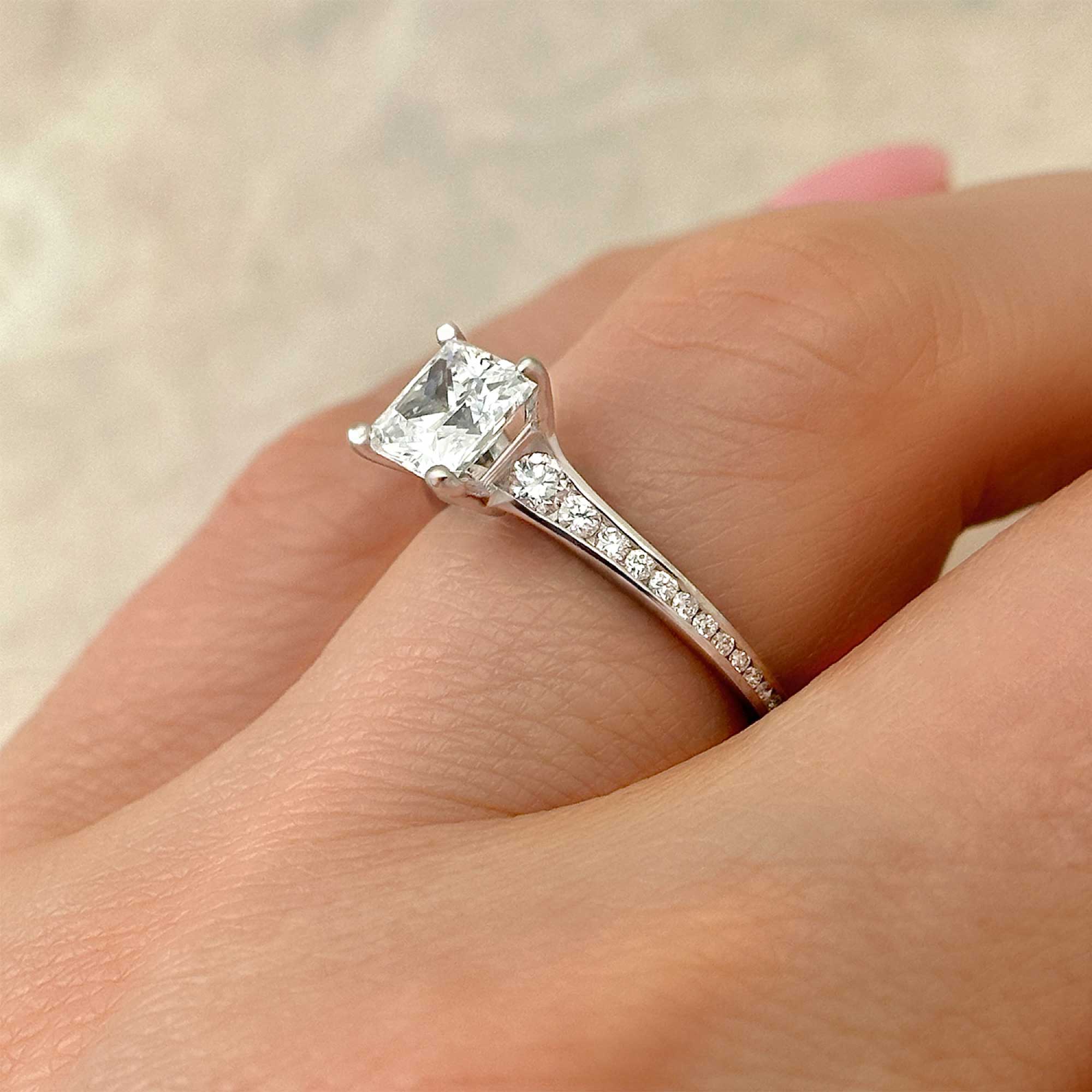 princess cut diamond engagement ring with channel accents on finger