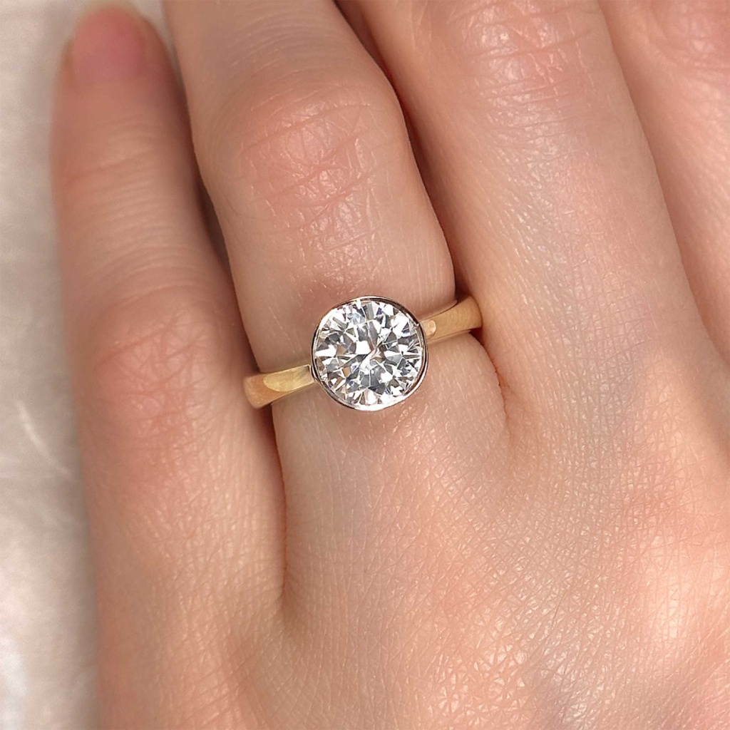 round brilliant diamond bezel set solitaire engagement ring on finger