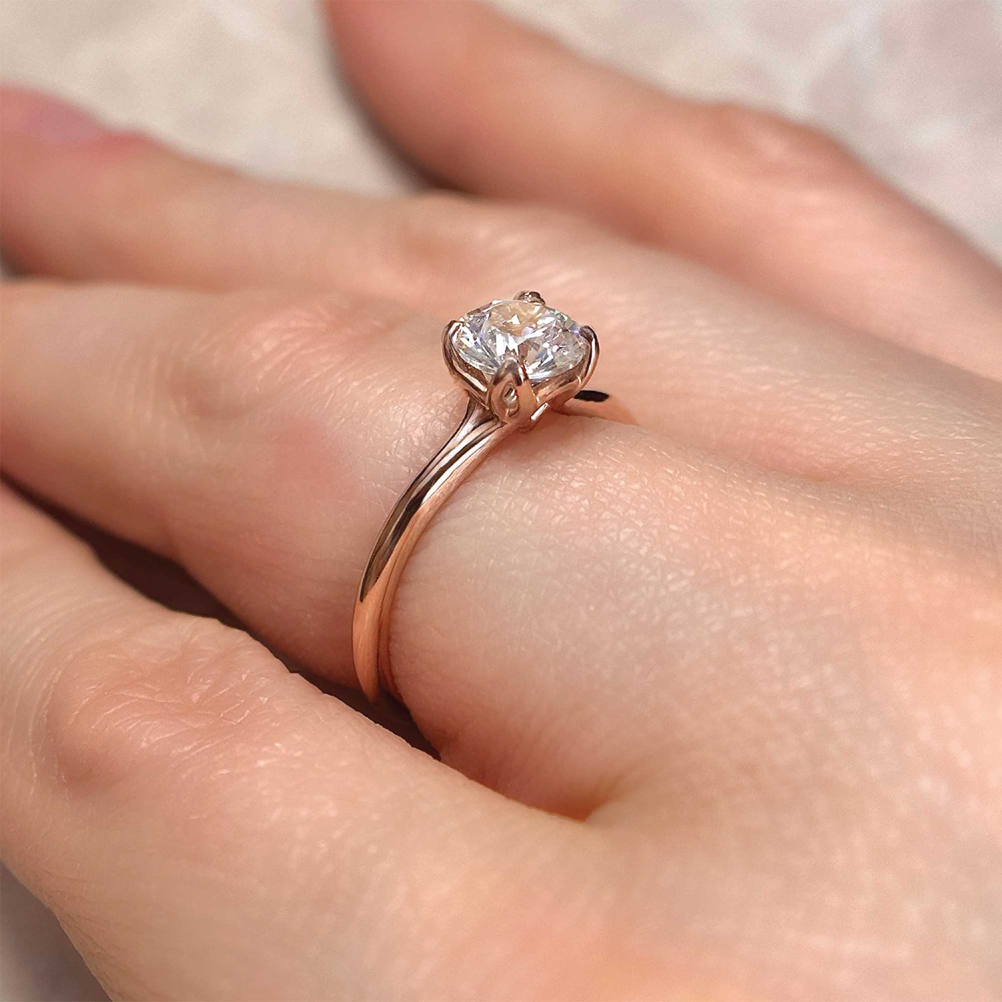 round brilliant diamond engagement ring with 4 prongs rose gold on finger alt view