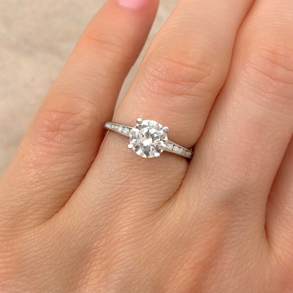 round brilliant diamond engagement ring with channel accents on finger alt view