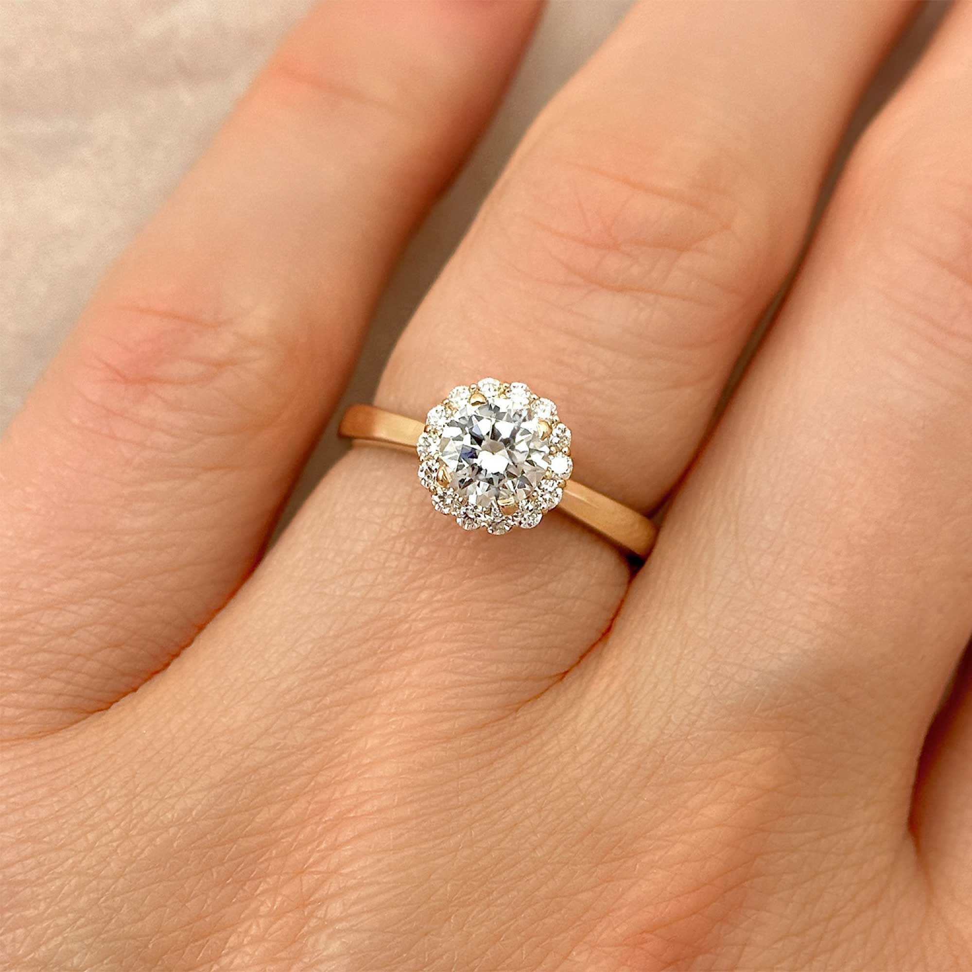round brilliant diamond engagement ring with diamond halo on finger alt view