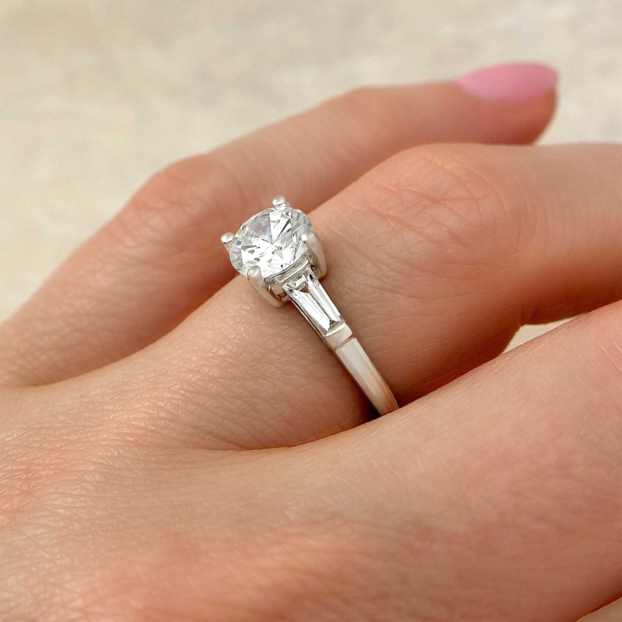 round brilliant diamond tapered baguette diamond engagement ring on finger